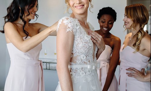 Bridesmaid helping bride get dressed