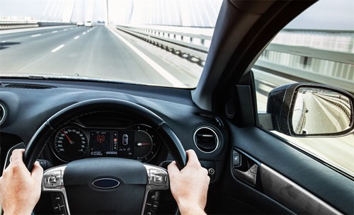 Person diving a car on a bridge, holding the steering wheel