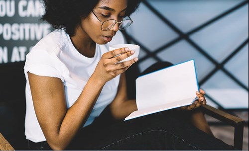 Woman drinking coffee and reading a book