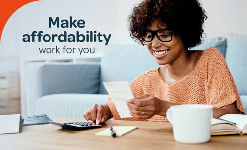 Woman sitting at table, smiling at receipt and using calculator