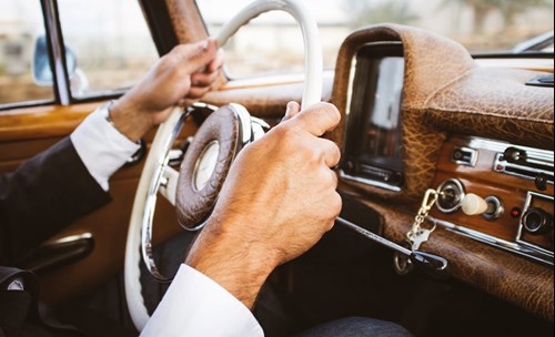 Person in a suite driving a vintage car