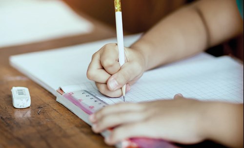 Child writing in a book with a pencil in a book